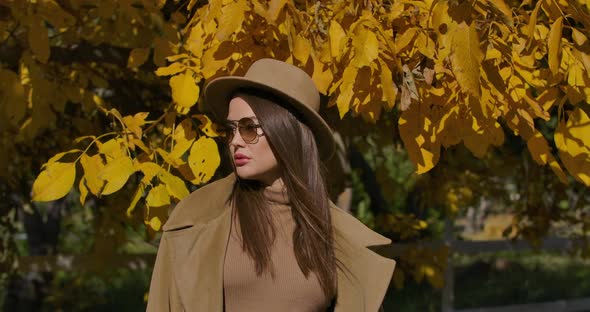 Portrait of a Confident European Girl in Brown Hat and Sunglasses Standing on the Background of