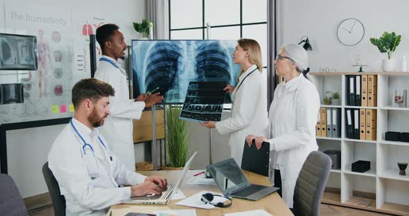 Doctors Holding Joint Meeting in Clinic Office and Discussing Patient's Chest X-ray and Lungs scan