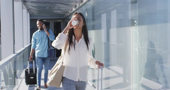 Video of diverse man and woman walking with suitcases and coffee