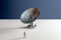 Minimalistic still life astronaut miniature looking at astronomical radio telescope landscape - PhotoDune Item for Sale