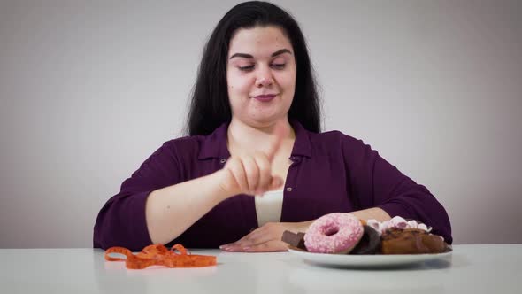 Portrait of Smiling Caucasian Obese Girl Sitting in Front of Sweets and Measure Tape. Fat Woman