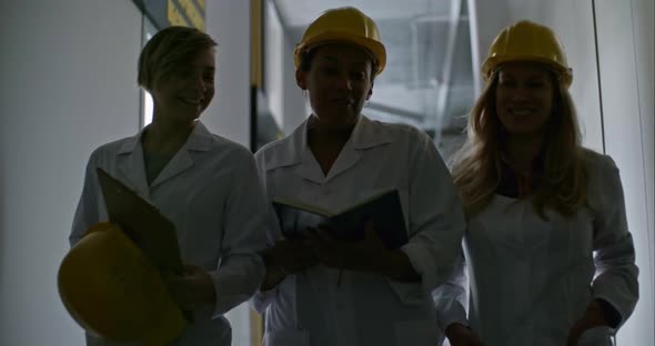 Female Engineers Walking through Corridor, Chatting and Laughing