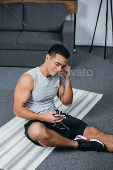 olding smartphone while sitting on  fitness mat