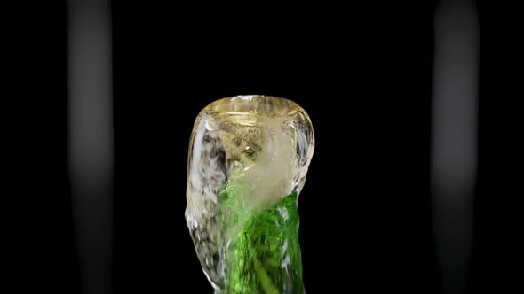 Macro Shot of Cap Popping Out of Green Glass Bottle and Explosion of Splash Carbonated Beer
