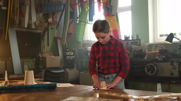 A Boy in a Plaid Shirt Makes a Paper Airplane