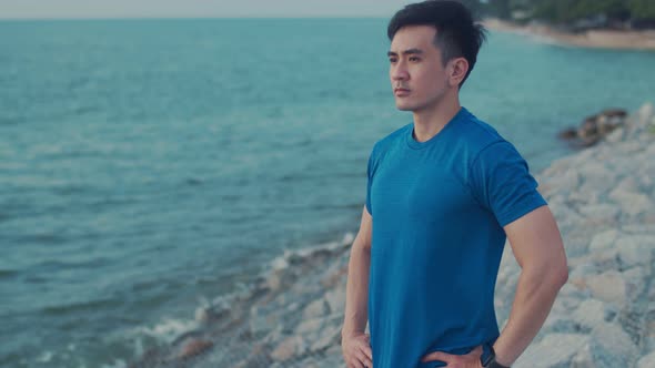 Man runner looks at the sea view while standing on the beach.