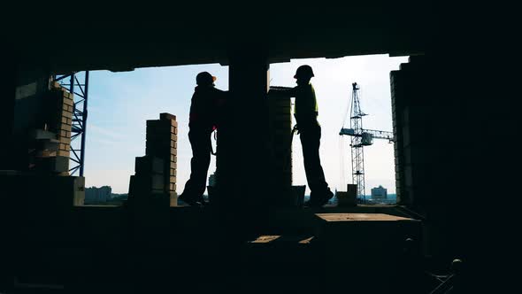 Workers in Uniform Laying Bricks at a Building Site.