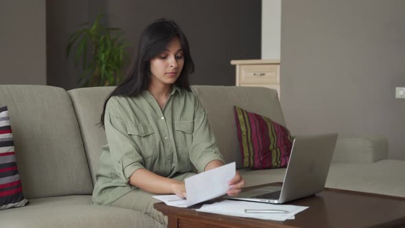 Serious Indian Lady Reading Bill Using Computer Making Online Payment at Home