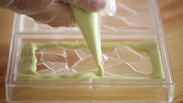 Woman preparing dessert, squeezing soft green cream out of a pastry bag