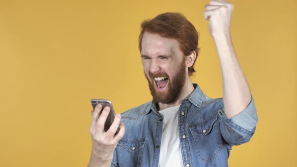 Redhead Man Excited for Success While Using Smartphone