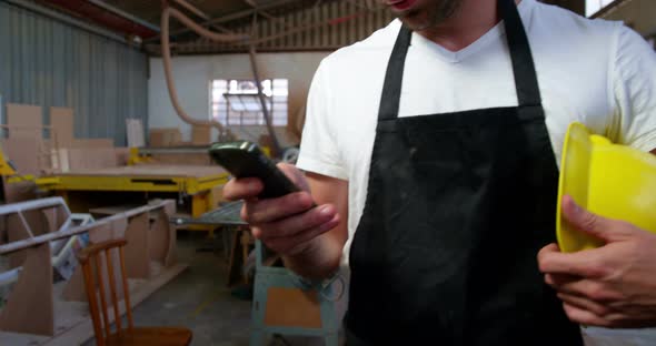 Attractive carpenter using his phone and smiling for camera