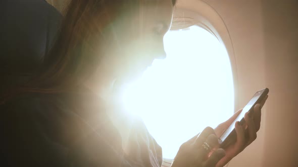 Amazing Close-up Shot of Young Happy Businesswoman Using Smartphone on Airplane Flight, Sunlight