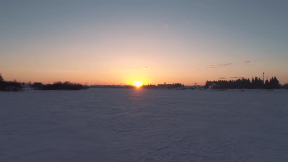 Aerial Over the Frozen River Surrounded with Forest at Sunset Siberia