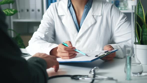 A Female Doctor Holds A Tablet With Tests And Consults A Patient In The Hospital. The Doctor