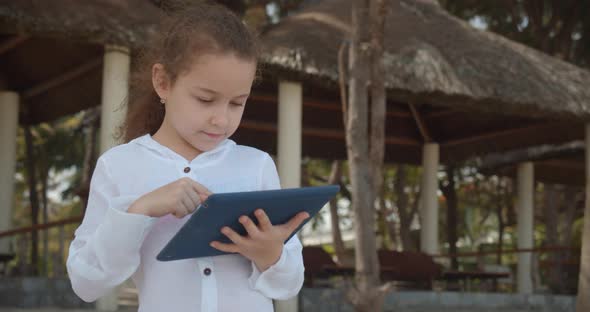 The Child Has a Rest Plays in the Tablet Outdoors