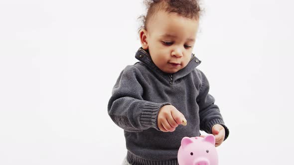 Cute Little Boy Putting a Coin Into the Pink Piggy Bank and Clapping His Hands  Savings Concept