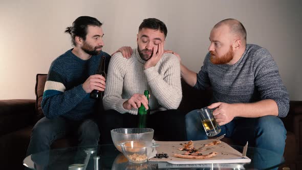 Unhappy Stressed Guy Drinking Beer Sitting on Sofa with Friends