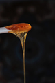 Sugaring paste drips from a wooden stick on a dark background. - PhotoDune Item for Sale