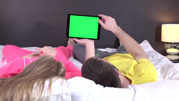 Young Sweet Couple at Bed Watching Something on Tablet Gadget, Green Screen