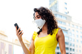 Woman with mask looking at mobile phone in the city - PhotoDune Item for Sale