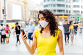Serious woman with mask looking at mobile phone in the city - PhotoDune Item for Sale