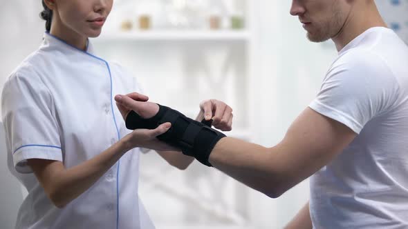 Professional Orthopedist Fixing Wrist Support Pleased Male Patient, Healthcare