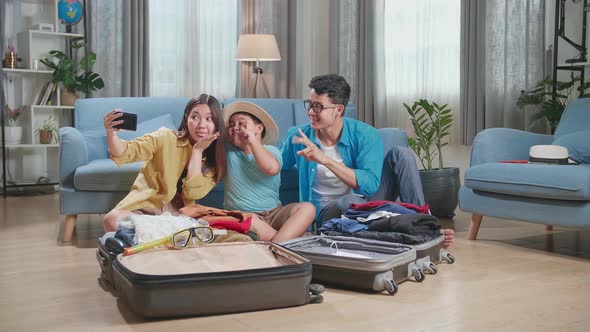 Asian Family Packing Clothes In A Suitcase And Selfie For A New Journey. Luggage For Travel Holidays