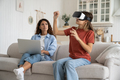 Curious teen girl using vr headset for study while mother working remotely on laptop - PhotoDune Item for Sale