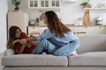 Friendly Caucasian woman and teenage girl entertain themselves sits on sofa in spacious bright house - PhotoDune Item for Sale