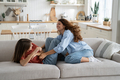 Mother and teen girl daughter enjoying time at home, tickling each other and laughing - PhotoDune Item for Sale