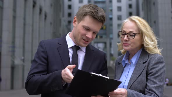 Young Business Man and Senior Female Colleague Discussing Deal Document, Work