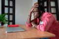 Upset young African guy freelancer touching forehead thinking about personal problems at workplace - PhotoDune Item for Sale
