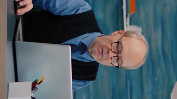 Vertical Video Senior Businessman Reading Reports Sitting in Front of Laptop