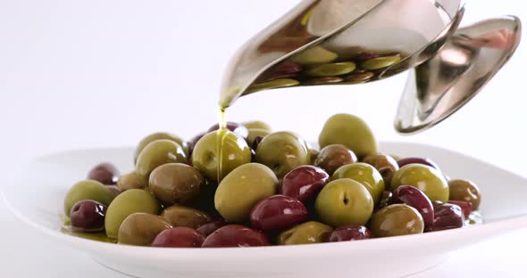 Olives in olive oil spin around themselves on white background, rotating