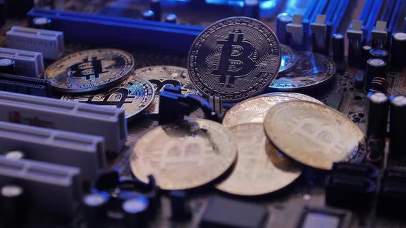 Golden coins with bitcoin symbol on electronic circuits in a computer mainboard.