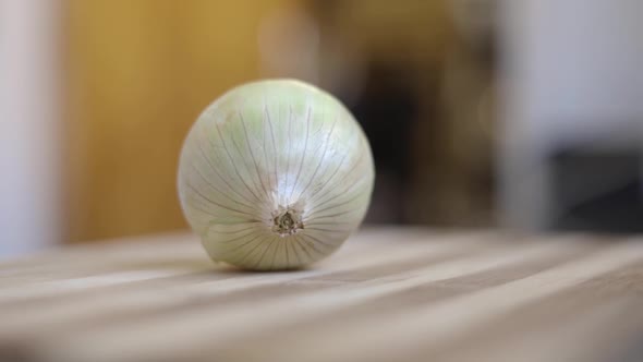 Static shot of a man starting to prepare an onion for peeling