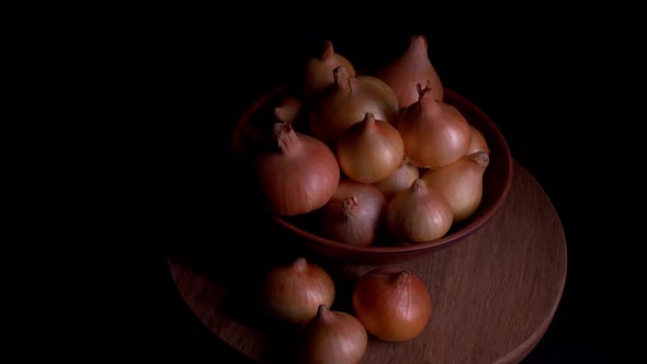 Pile of Whole Bulbs of Raw Onion in Ceramic Bowl on Table