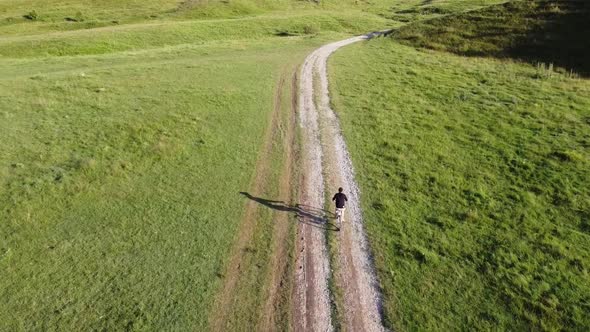 Aerial footage of a male ridding his bike on a country road on a sunny summer day