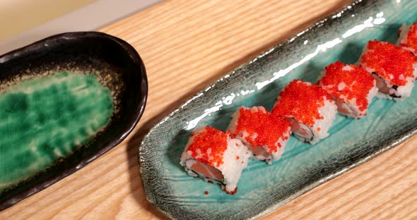 Delicious Sushi Rolls In A Plate Topped With Orange Roe (Tobiko) - high angle panning shot, slow mot
