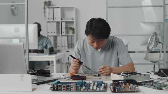 Asian Female Engineer Soldering Electronics in Laboratory