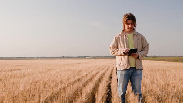 Farmer Working with Tablet Computer on Wheat Field