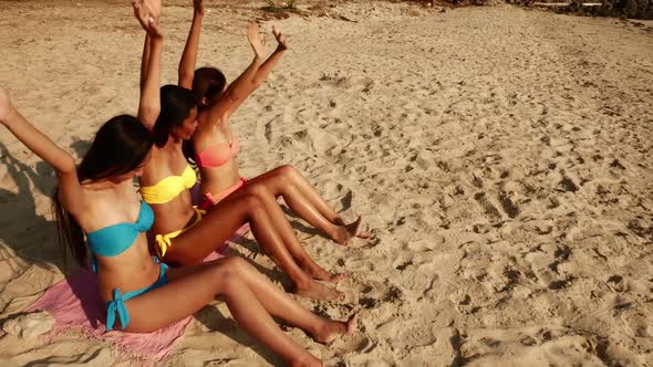 Group of women in bikini sitting and relaxing on the beach