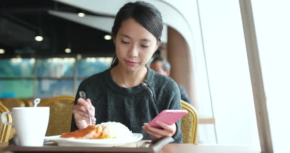 Busy woman having lunch in restaurant with using mobile phone