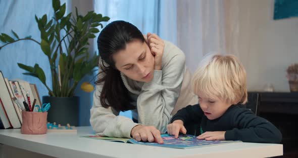 Young Mother with Preschool Child Boy Reading the Book with Labyrinths