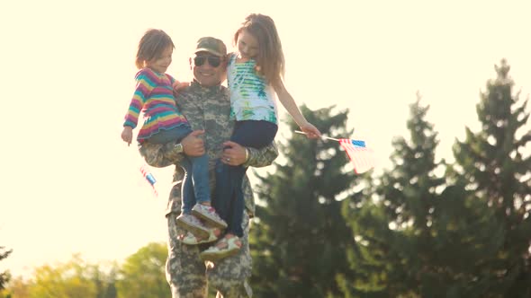 Soldier Walking Holding Two Adorable Little Girls in the Park