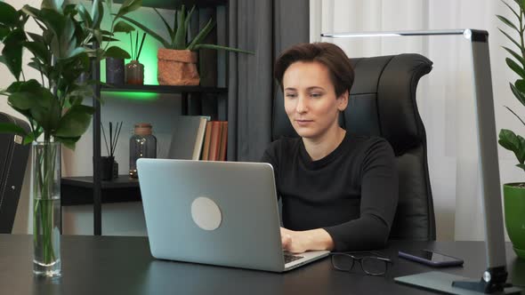 Woman is working on laptop computer in stylish office. Businesswoman is using notebook at workplace