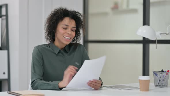 African Woman Celebrating While Reading Papers