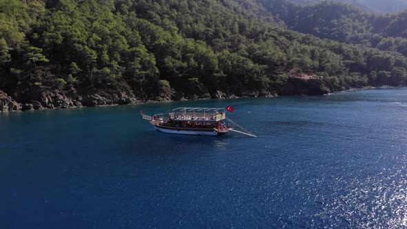 Drone Shooting of a Yacht with Tourists on the Deck During an Excursion Off the Coast of a Mountain