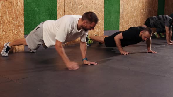 Strong Fit Athletic Men Doing Push Up Exercises in Loft Style Industrial Gym