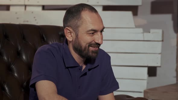 Happy Father with Beard Sitting on Leather Armchair